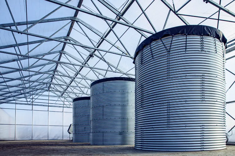 Fotografía de dos tanques grandes color gris que forman parte de equipos de tratamiento de agua colocados al aire libre.
