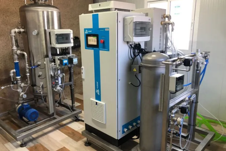 Fotografía de un hombre vestido de negro de pie frente a las instalaciones de sistemas de ozono para agua.